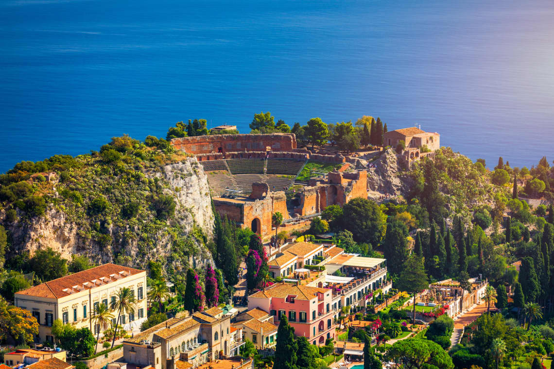 Ruins of Ancient Greek theater in Taormina, Sicily, Italy with Ocean in the Background