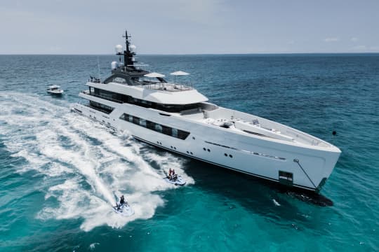 White Yacht on the waters with People on Jetskis Next to It