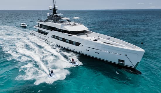 White Yacht on the waters with People on Jetskis Next to It