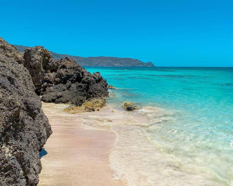 Elafonissi Beach is renowned for its pink sand, shallow turquoise waters, and natural lagoon